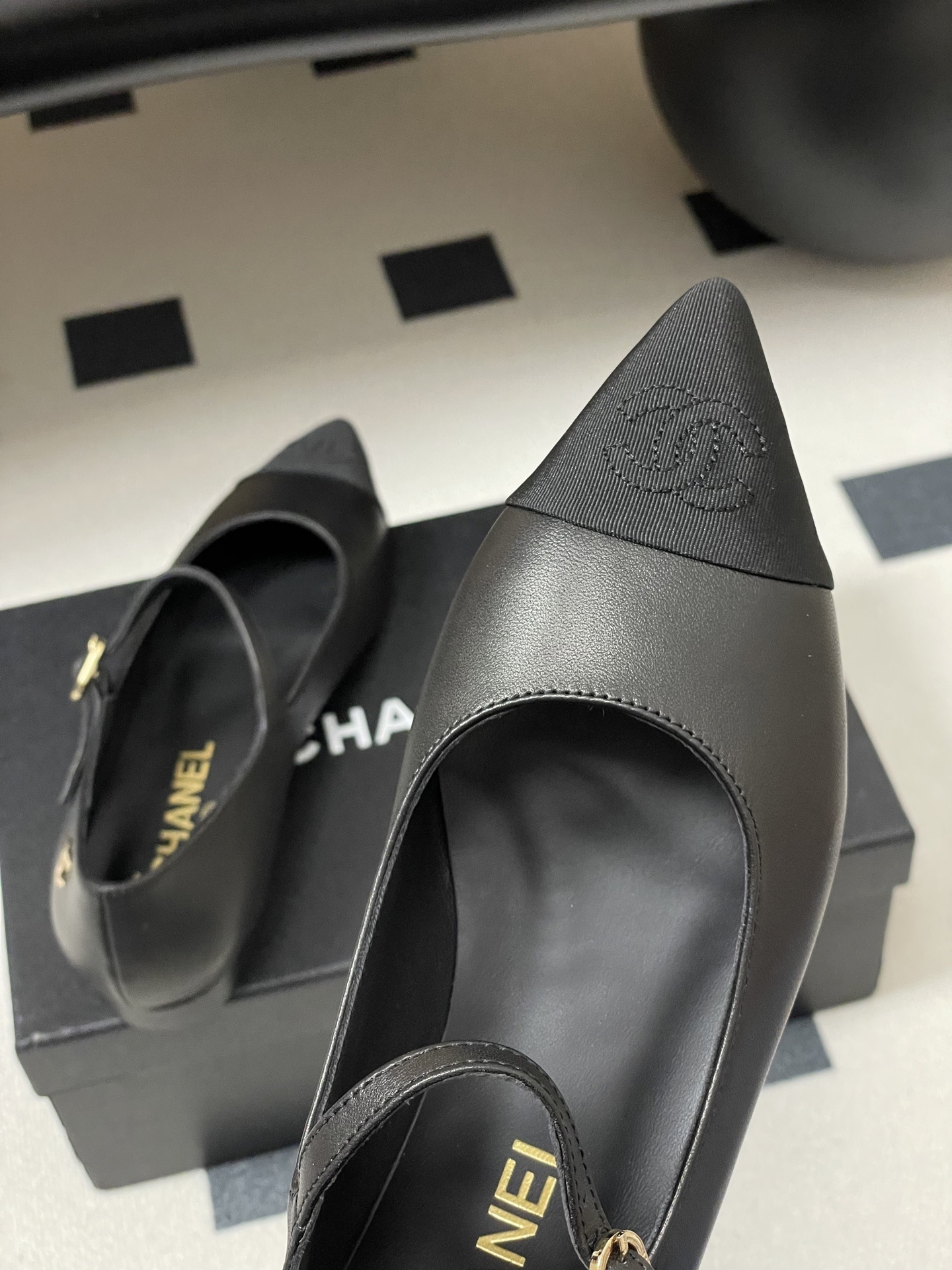Pair of Chanel black leather Mary Jane pointed toe flats with gold CC logo and buckled strap on a black surface - Hình 9