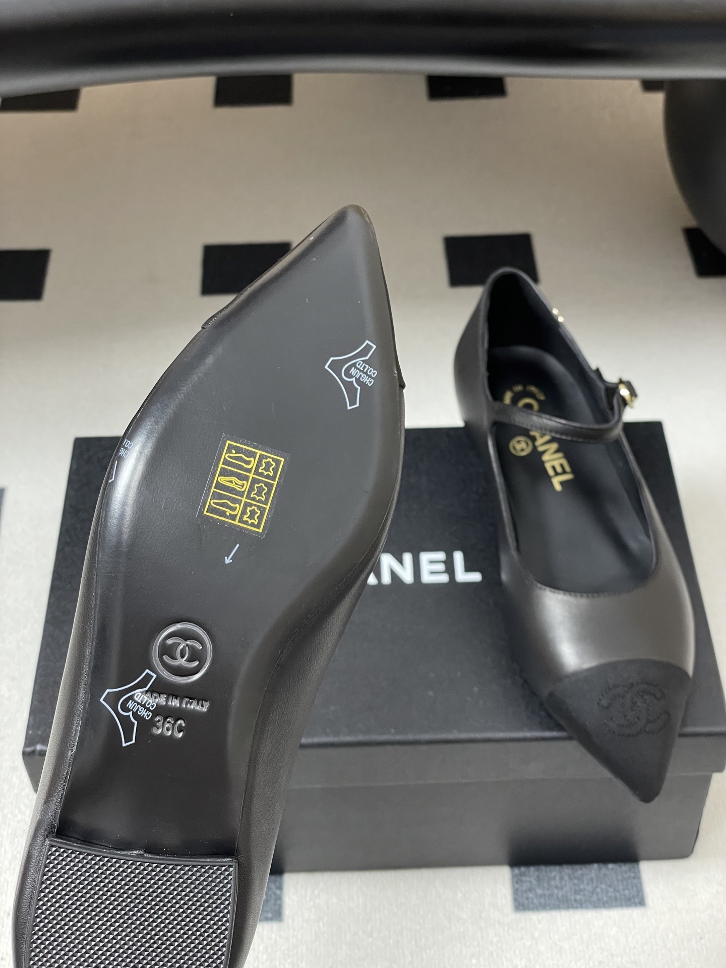 Pair of Chanel black leather Mary Jane pointed toe flats with gold CC logo and buckled strap on a black surface - Hình 8