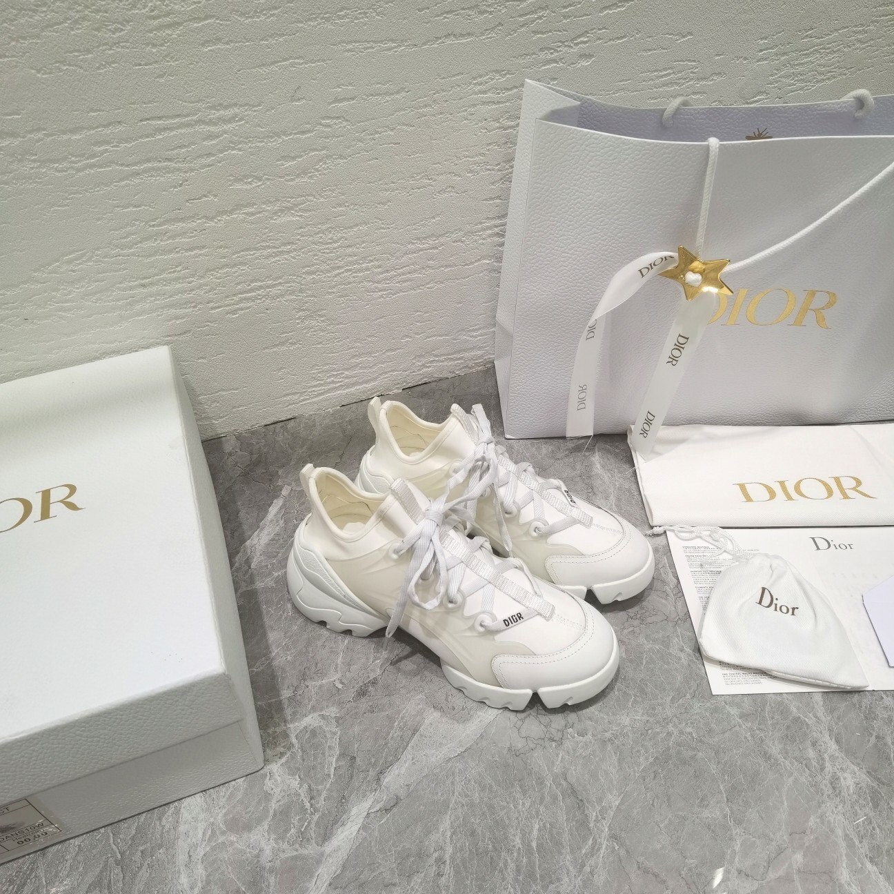 A pair of white Dior Vibe sneakers for women featuring a chunky sculpted sole and Dior logo on the heel, shown with original luxury packaging including box and gift bag.