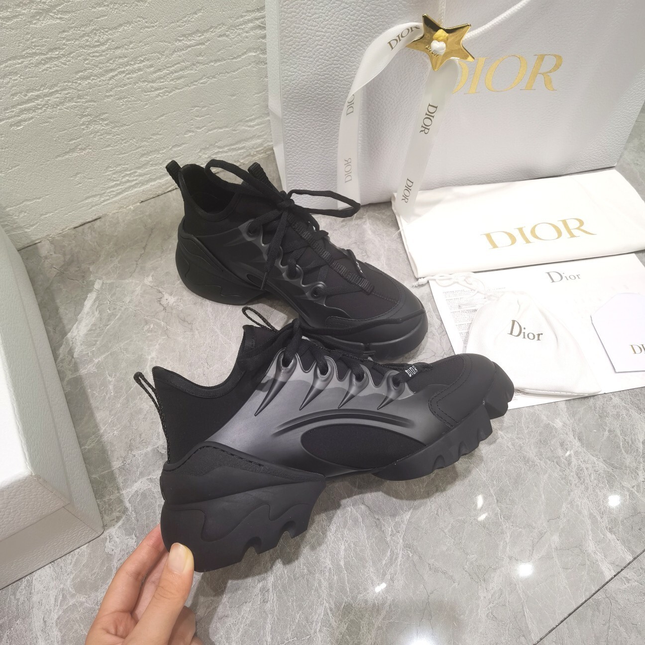 Close-up of Dior Vibe women's sneakers in black technical fabric with luxury Dior packaging and shopping bag