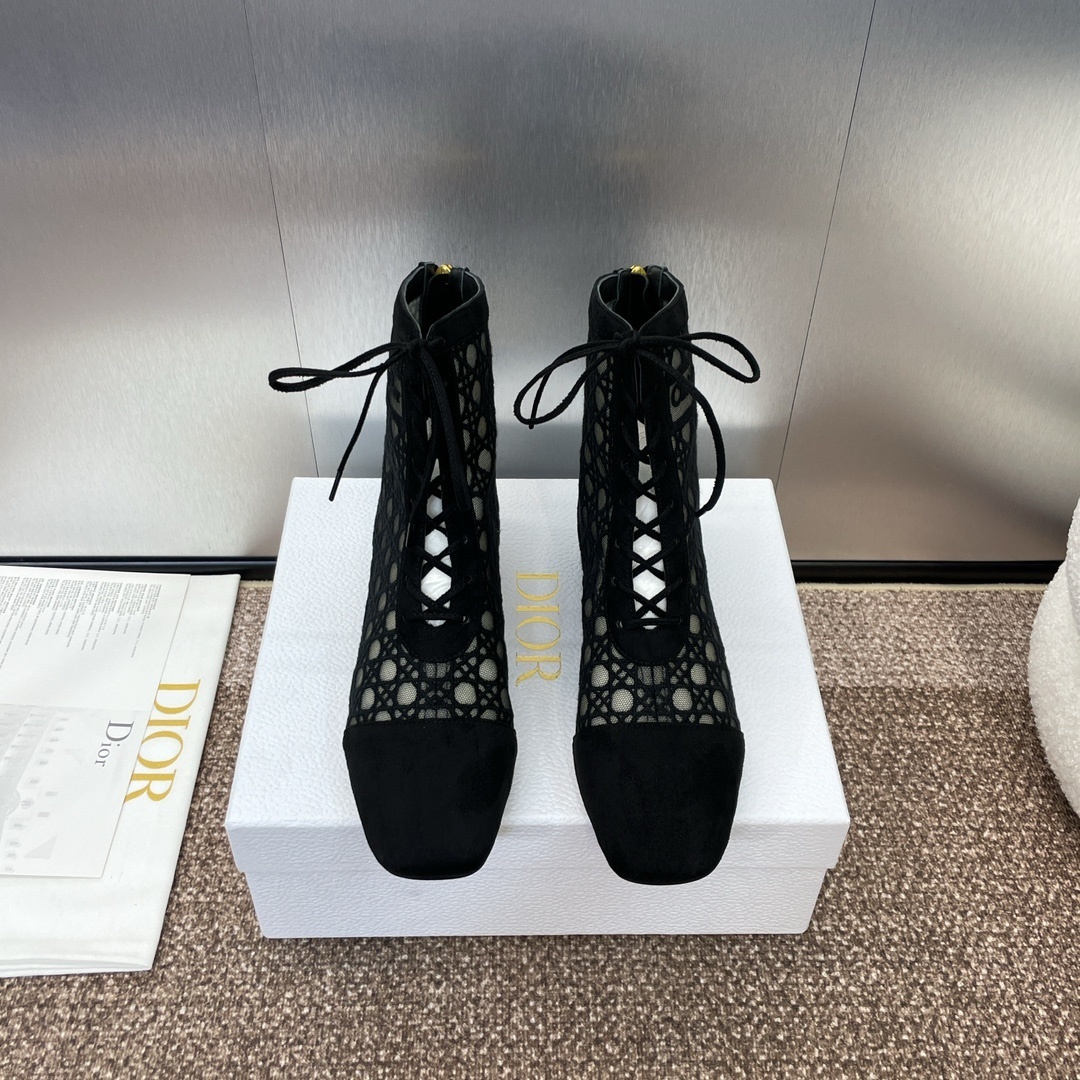 A pair of black Dior D-Fight lace-up ankle boots with Cannage mesh embroidery and suede toe caps, displayed on a white Dior shoebox.