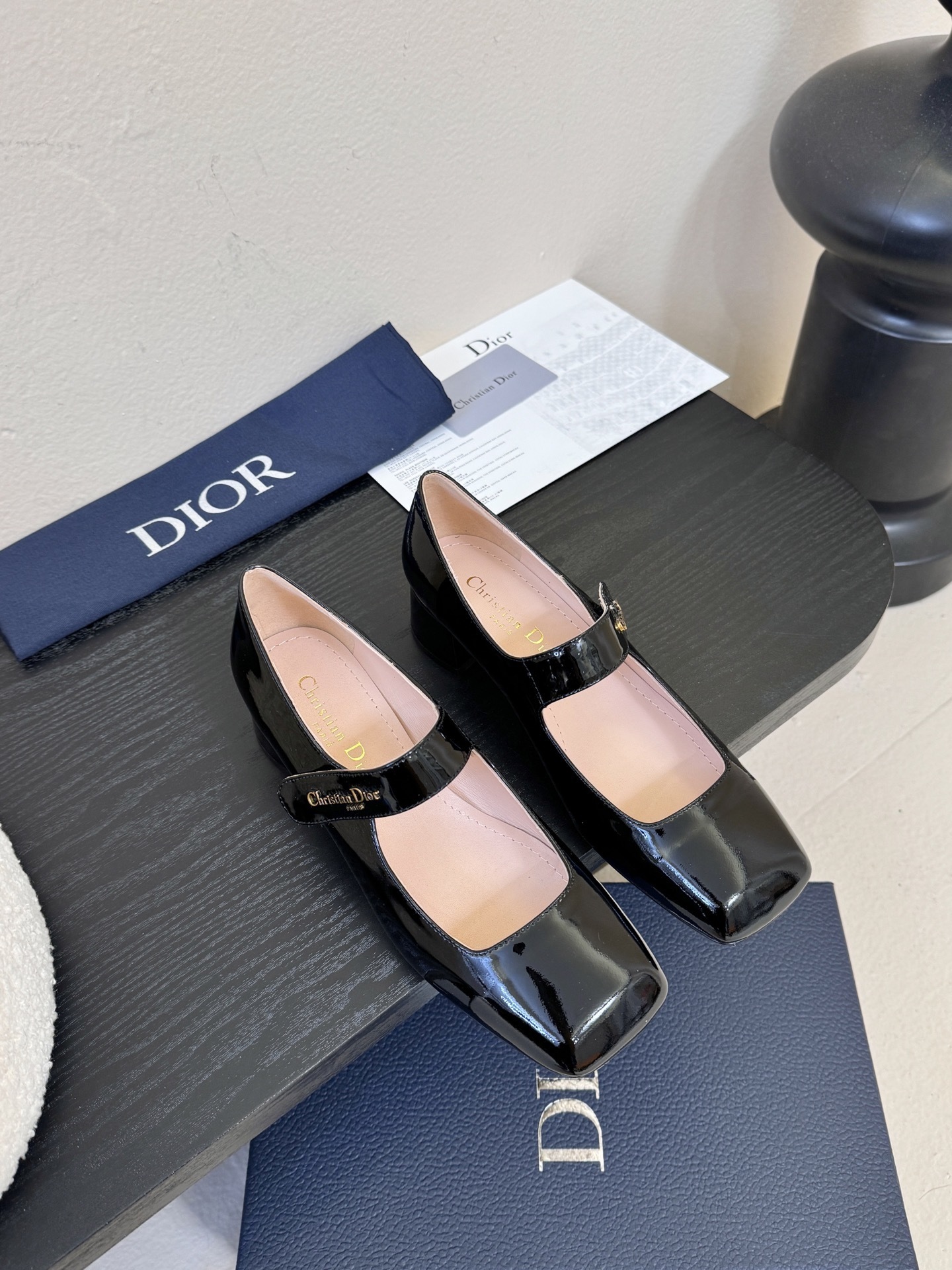 Pair of Christian Dior black patent leather Mary Jane pumps with square toes and block heels featuring gold-tone logo straps.