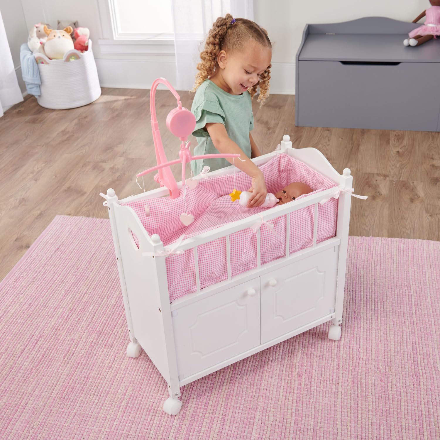Badger Basket Wooden Toy Doll Bed with Storage, Mobile, and Bedding to Pretend and Play - Includes Wheels and Free Personalization Kit - White with Pink Gingham Fabric